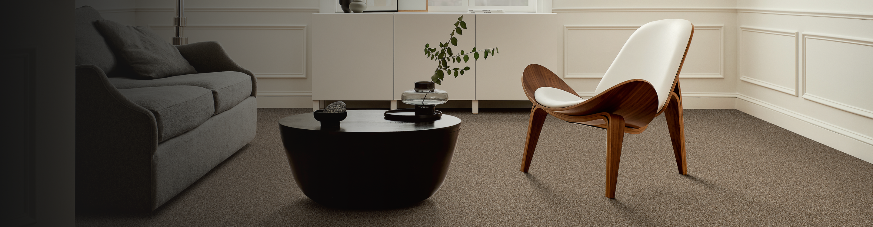 beige carpet flooring in contemporary living room with black coffee table, modern wood chair and abstract art